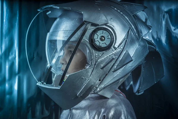 探险家 男孩扮演一个宇航员与空间头盔和金属西装超过银色背景 — 图库照片