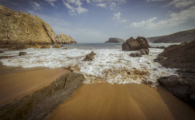 Seyahat, plaj yaz aylarında taşlarla. Playa de la Arna Santander, İspanya 