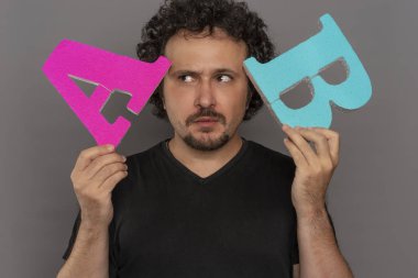 Seçim, dönüşüm huni, A / B testi pazarlama ve online reklam. Esmer adam renkli harfler A ve B yüz ifadeleri ile elinde tutan