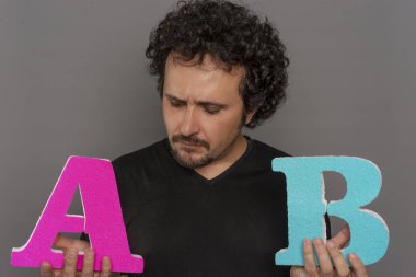 Karşılaştırma, dönüşüm huni, A / B testi pazarlama ve online reklam. Esmer adam renkli harfler A ve B yüz ifadeleri ile elinde tutan