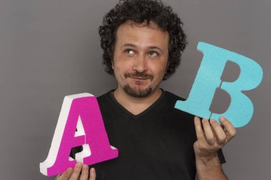 dönüşüm huni, A / B testi pazarlama ve online reklam. Esmer adam renkli harfler A ve B yüz ifadeleri ile elinde tutan