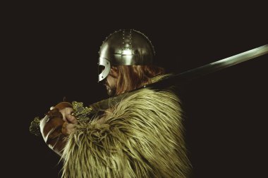Metalik miğferli ve hayvan derili Viking savaşçısı. deri eldivenler, altın süslemeleri ve çelik kılıç ile kırmızı ahşap kalkan