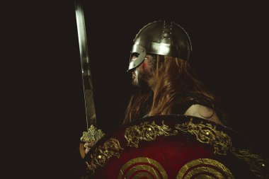 Şövalye, metalik miğferli ve hayvan derili Viking savaşçısı. deri eldivenler, altın süslemeleri ve çelik kılıç ile kırmızı ahşap kalkan
