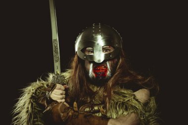 Şövalye, metalik miğferli ve hayvan derili Viking savaşçısı. deri eldivenler, altın süslemeleri ve çelik kılıç ile kırmızı ahşap kalkan