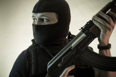 Hırsız, av tüfeği ve kurşun geçirmez yelek ile silahlı adam