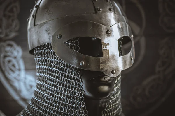 Traditional Vikings, viking helmet with chain mail on a red shield with golden shapes of sun, weapons for war