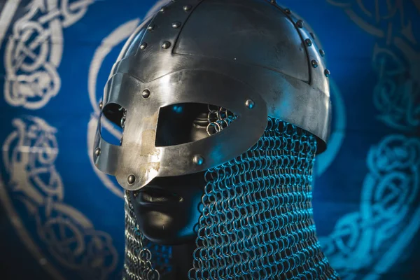 Weapons Viking helmet with chain mail of iron on red shield of wood and golden triskel