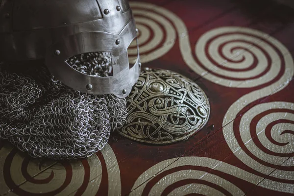 Triskel, Vikings, viking helmet with chain mail on a red shield with golden shapes of sun, weapons for war