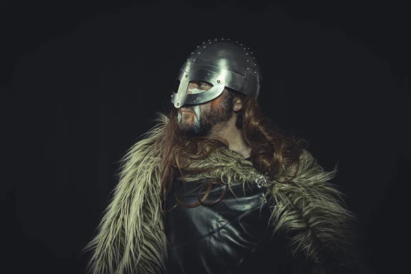 Viking, Scandinavian warrior with helmet and war paintings, wears a sword and a cape of animal skin