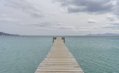 Ahşap iskele, Akdeniz 'deki sakin turkuaz sular, sakin bir tatil manzarası.
