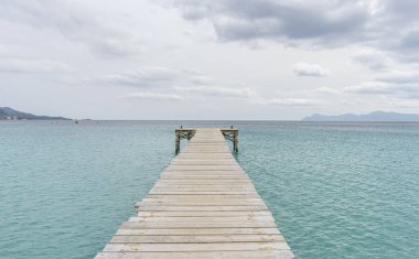Ahşap iskele, Akdeniz 'deki sakin turkuaz sular, sakin bir tatil manzarası.