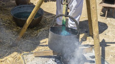 İspanya'da bir ortaçağ fuarında renkli boyalar ile bir kazan kumaş ve yün el yapımı boyama