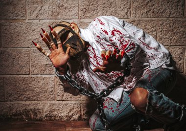 Cadılar Bayramı tatili kutlaması, cosplay. Kale arka plan daki insan iblisi. Zincirli şeytan, kırmızı kan. Cehennem, ölüm, kötülük, korku kavramı. Kanlı lekeleri olan şeytan