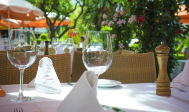 Beyaz boş plakalar şarap gözlükleri, açık havada terasta evde ahşap masa ayarı, örgü pot hiçbir insan üzerinde bitki kapatın. Yaz terası kafede servis edilen masa