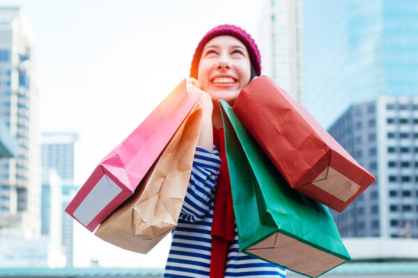 Portrait of an excited beautiful young girl wear shirt and wool hat holding many shopping bags and smile. With copy space. Woman shopper smiling happy. Beautiful young Caucasian. lifestyle, discount