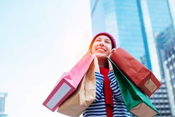 Portrait of an excited beautiful young girl wear shirt and wool hat holding many shopping bags and smile. With copy space. Woman shopper smiling happy. Beautiful young Caucasian. lifestyle, discount