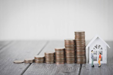 Minyatür insanlar küçük bir rakam sikke para yığını adım modeli beyaz ev, gayrimenkul yatırım ve house mortgage mali kavramı, büyüme büyüyen kadar ayakta eve korumak, sigorta. Kopya alanı ile.