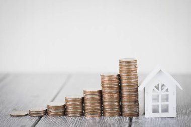 Para madeni para yığınının adım büyüme modeli beyaz ev ahşap masa üzerinde büyüyor. Gayrimenkul yatırım ve house mortgage mali kavramı, eve korumak, sigorta. Metniniz için kopya alanı ile.
