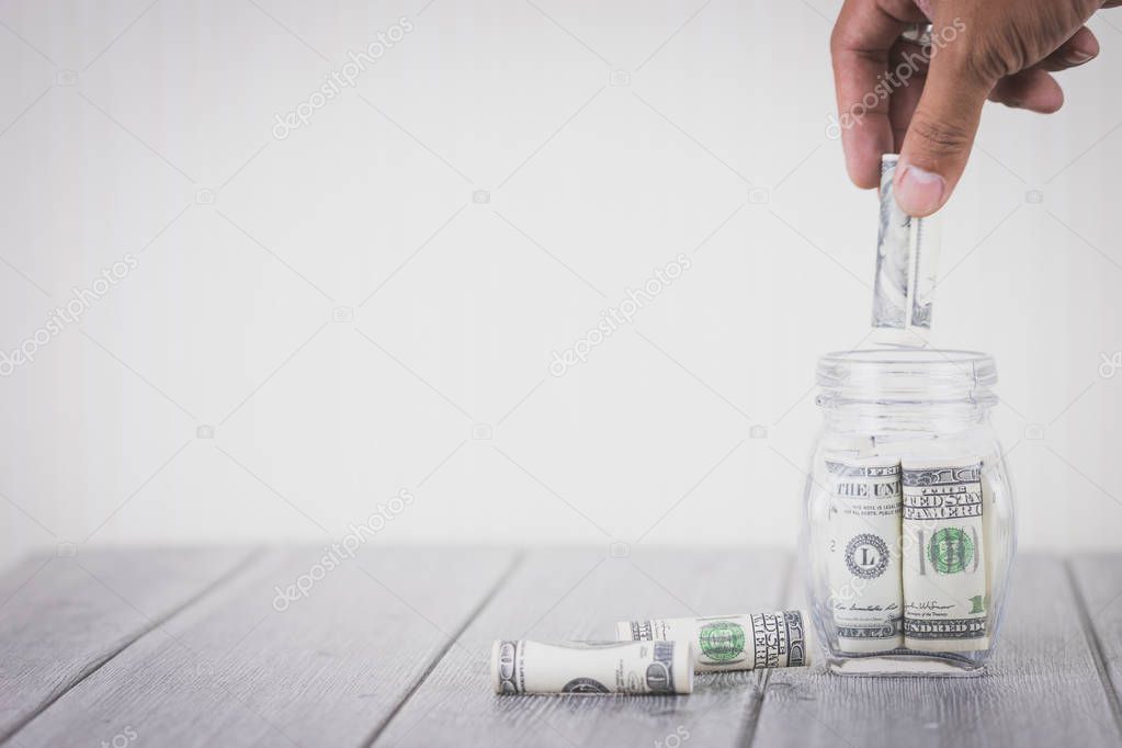 Businessman hand putting money hundred dollars in glass bottle, Concept of saving money, Business investment financial plan, Sustainable growth and stability in the future, With copy space