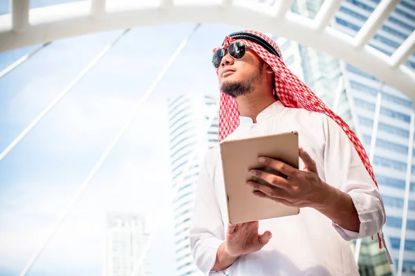 Handsome arab business man hold the digital tablet and looking to left side. Arab business man standing outside office. Finishing up a meeting, Connection concept. with copy space