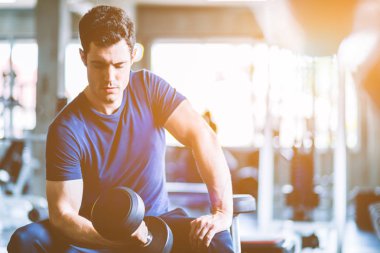 Beyaz yakışıklı genç ve büyük kas spor içinde uygun. Genç adam bir spor salonunda bir egzersiz dersi sırasında dumbbell tutarak. Sağlıklı spor yaşam tarzı, Fitness kavramı.