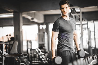 Beyaz yakışıklı genç ve büyük kas spor içinde uygun. Genç adam bir spor salonunda bir egzersiz dersi sırasında dumbbell tutarak. Sağlıklı spor yaşam tarzı, Fitness kavramı.