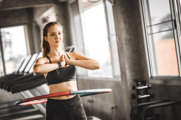 Güzel beyaz genç kadının adım bel ileriye doğru duruş doldurma hula hoop yapması. Genç kadın bir spor salonunda bir egzersiz dersi sırasında hula hoop yapıyor. Sağlıklı spor yaşam tarzı, Fitness, sağlıklı kavramı.