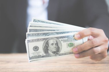 El para dolar faturaları ahşap masa üzerinde tutan işadamı kapatın. Yolsuzluk, iş yolsuzluk, rüşvet kavram olarak kullanarak. Metniniz için kopya alanı ile.