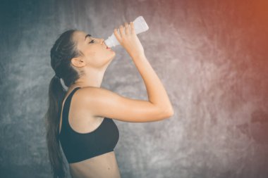 Genç kadın spor salonunda egzersiz sonrası şişeden süt içme uygun. Güzel kadın spor salonunda spor içinde sağlık içecek ve gülümseme ile bir mola. Sağlıklı kavramı, fitness, spor, yaşam biçimi.