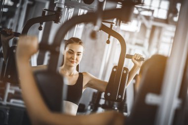 Güzel genç kadın egzersiz egzersiz jimnastik salonu makinedeki uygun. Memnun gülümseyen kız onu eğitim süreci ile keyfini çıkarın. Fitness, sağlıklı, spor, yaşam kavramı
