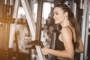 Güzel genç kadın egzersiz egzersiz jimnastik salonu makinedeki uygun. Memnun gülümseyen kız onu eğitim süreci ile keyfini çıkarın. Fitness, sağlıklı, spor, yaşam kavramı