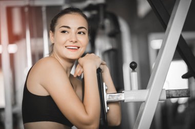 Güzel genç kadın egzersiz egzersiz jimnastik salonu makinedeki uygun. Memnun gülümseyen kız onu eğitim süreci ile keyfini çıkarın. Fitness, sağlıklı, spor, yaşam kavramı