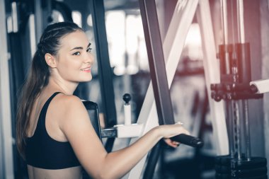 Güzel genç kadın egzersiz egzersiz jimnastik salonu makinedeki uygun. Memnun gülümseyen kız onu eğitim süreci ile keyfini çıkarın. Fitness, sağlıklı, spor, yaşam kavramı