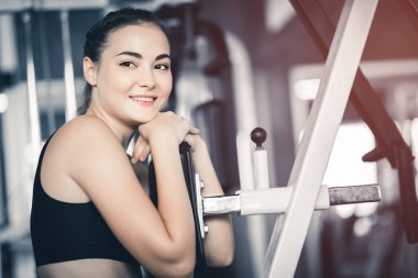 Güzel genç kadın egzersiz egzersiz jimnastik salonu makinedeki uygun. Memnun gülümseyen kız onu eğitim süreci ile keyfini çıkarın. Fitness, sağlıklı, spor, yaşam kavramı