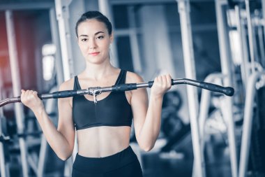 Güzel genç kadın beyaz spor giyim kameraya poz uygun. Bir spor salonunda bir egzersiz dersi sırasında halter tutan genç kadın. Sağlıklı spor yaşam tarzı, Fitness kavramı. Kopya alanı ile.