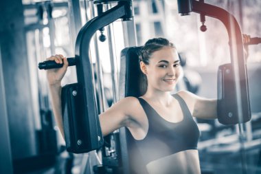 Güzel genç kadın egzersiz egzersiz jimnastik salonu makinedeki uygun. Memnun gülümseyen kız onu eğitim süreci ile keyfini çıkarın. Fitness, sağlıklı, spor, yaşam kavramı