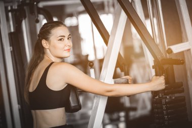 Güzel genç kadın egzersiz egzersiz jimnastik salonu makinedeki uygun. Memnun gülümseyen kız onu eğitim süreci ile keyfini çıkarın. Fitness, sağlıklı, spor, yaşam kavramı