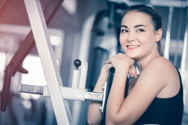 Güzel genç kadın egzersiz egzersiz jimnastik salonu makinedeki uygun. Memnun gülümseyen kız onu eğitim süreci ile keyfini çıkarın. Fitness, sağlıklı, spor, yaşam kavramı
