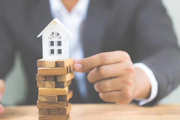 Model beyaz ev ahşap blok tutan işadamı el. Yatırım risk ve belirsizlik Emlak Konut piyasası. Gayrimenkul yatırım ve ev mali kavramı mortgage. kopya alanı ile