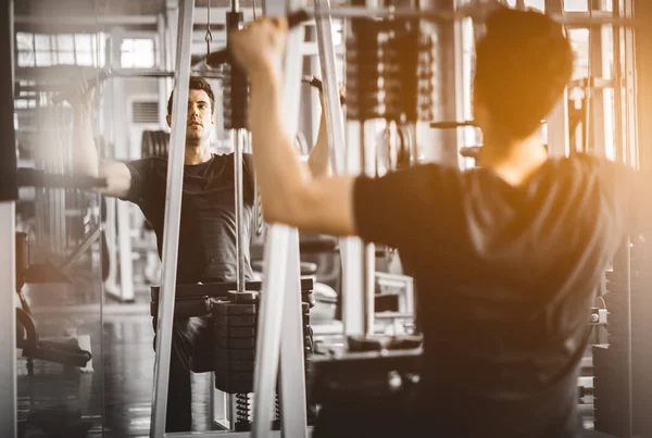 Fit caucasian handsome and big muscle workout in sportswear. Young man exercise with machine in a gym. Healthy sports lifestyle, Fitness concept.