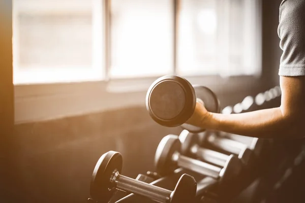 Beyaz yakışıklı genç ve büyük kas spor içinde uygun. Genç adam bir spor salonunda bir egzersiz dersi sırasında dumbbell tutarak. Sağlıklı spor yaşam tarzı, Fitness kavramı.