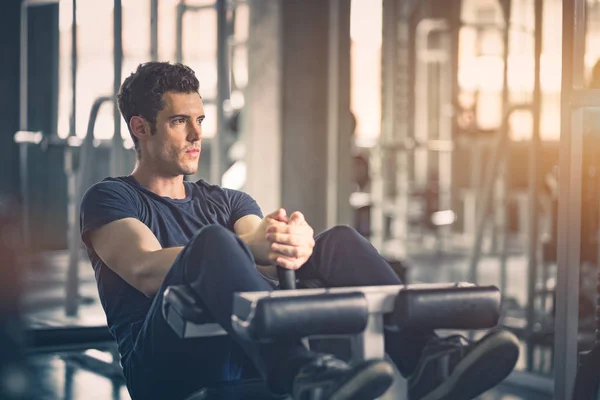 Spor salonu, Fitness, spor, sağlıklı, yaşam kavramı. Uygun genç adam spor giyim makinede ups sit. Yakışıklı adam oturup çekirdek karın kasları fitness eğitim salonunda güçlendirmek için egzersiz.