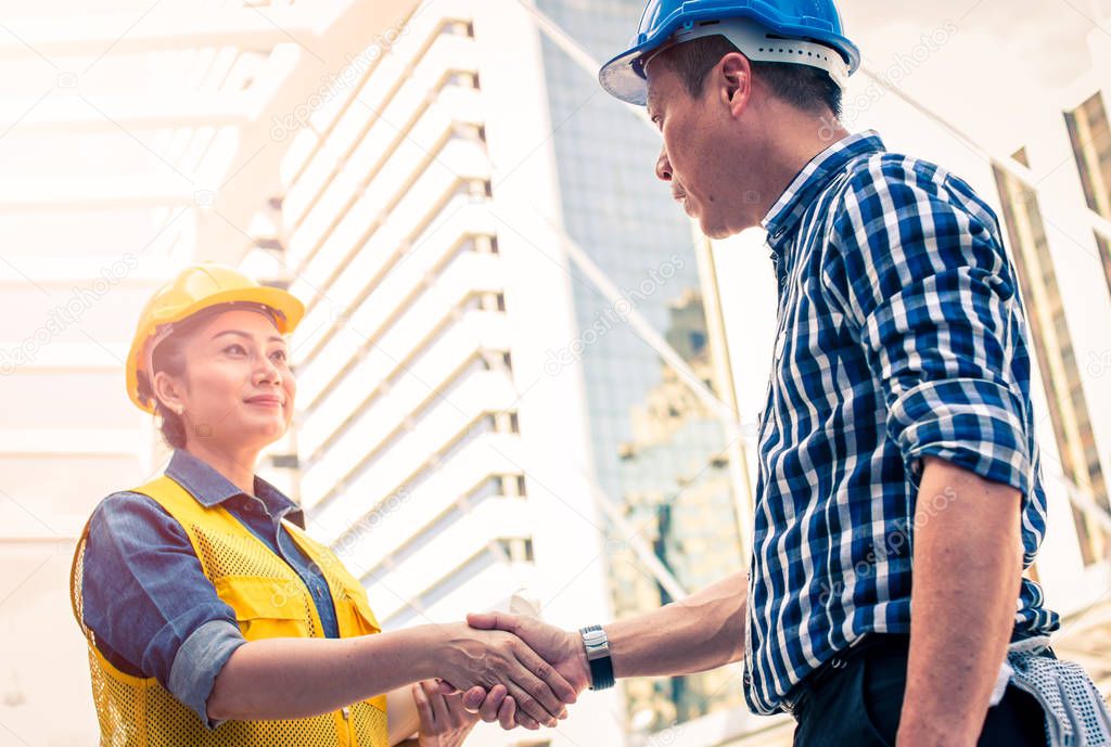 Construction and engineer concept. Construction worker in protective uniform shaking hands meeting for architectural project working with partner. Worker and customer having agreement in factory.