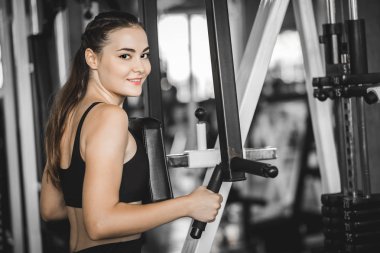 Güzel genç kadın egzersiz egzersiz jimnastik salonu makinedeki uygun. Memnun gülümseyen kız onu eğitim süreci ile keyfini çıkarın. Fitness, sağlıklı, spor, yaşam kavramı