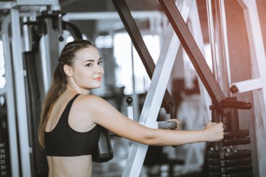 Güzel genç kadın egzersiz egzersiz jimnastik salonu makinedeki uygun. Memnun gülümseyen kız onu eğitim süreci ile keyfini çıkarın. Fitness, sağlıklı, spor, yaşam kavramı