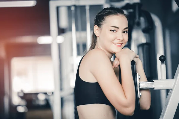 stock image Fit beautiful young woman exercise workout on machine in gym. Glad smiling girl is enjoy with her training process. Concept of fitness, Healthy, Sport, Lifestyle