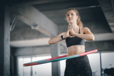 Güzel beyaz genç kadının adım bel ileriye doğru duruş doldurma hula hoop yapması. Genç kadın bir spor salonunda bir egzersiz dersi sırasında hula hoop yapıyor. Sağlıklı spor yaşam tarzı, Fitness, sağlıklı kavramı.