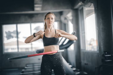 Güzel beyaz genç kadının adım bel ileriye doğru duruş doldurma hula hoop yapması. Genç kadın bir spor salonunda bir egzersiz dersi sırasında hula hoop yapıyor. Sağlıklı spor yaşam tarzı, Fitness, sağlıklı kavramı.