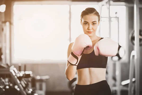 Fit beautiful woman boxer hitting a huge punching bag exercise class in a gym. Boxer woman making direct hit dynamic movement. Healthy, sports, lifestyle, Fitness, workout concept. With copy space.