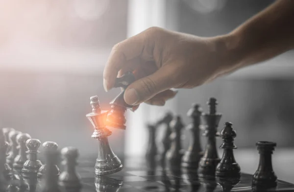 Business competition strategy and business success concept. Hand of two businessman moving for fighting dark king chess piece on chessboard game.